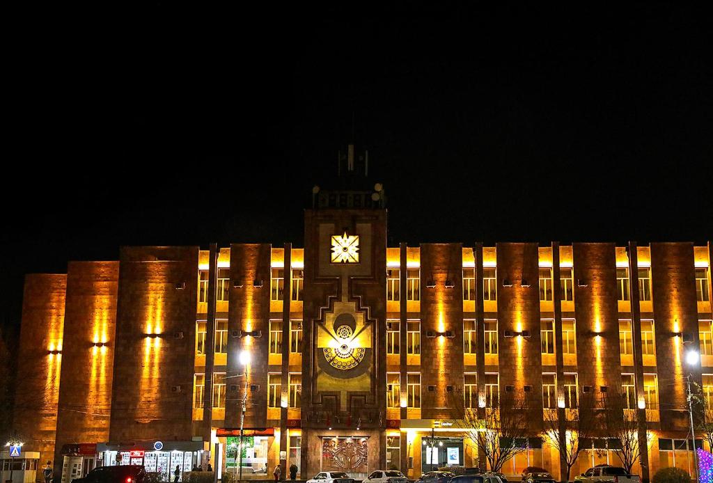 un gran edificio con una torre de reloj delante de él en Richmind Hotel en Vagharshapat