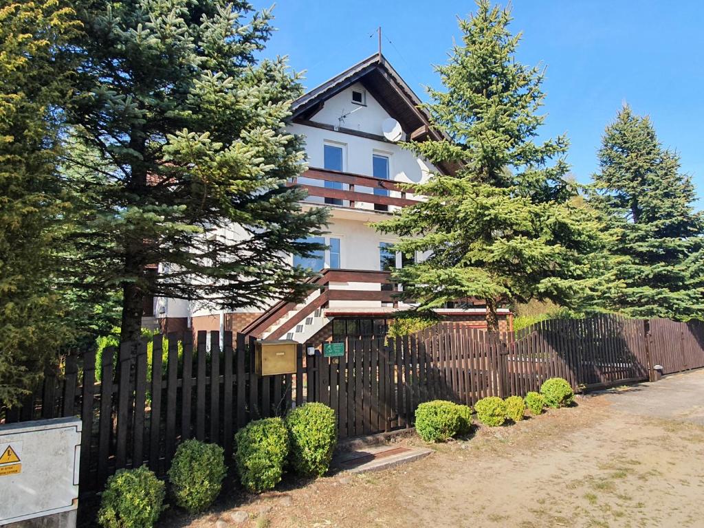 une maison avec une clôture noire et des arbres dans l'établissement Przestronny, komfortowy dom, à Swornegacie