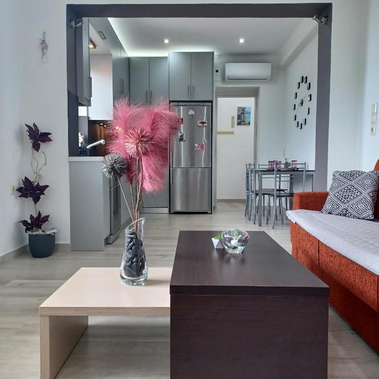 a living room with a vase with pink flowers in it at Zoggos Apartment in Áyios Pétros
