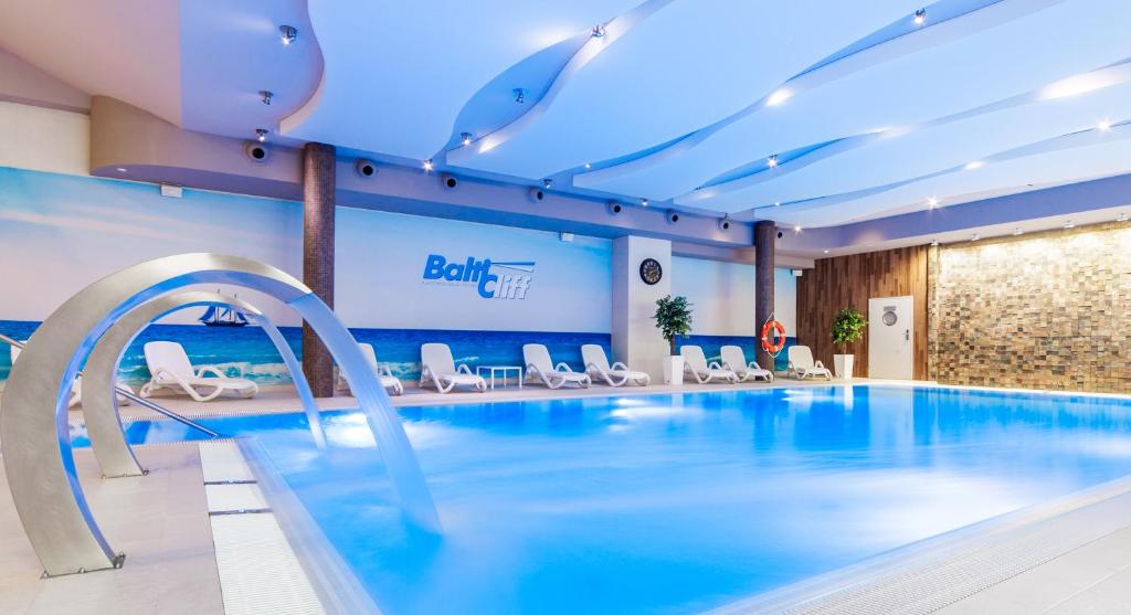 a swimming pool in a hotel with white chairs at Baltic Cliff Apartamenty in Niechorze