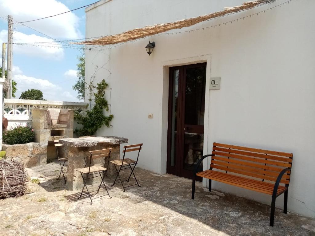 a patio with a bench and a table and chairs at Masseria Chianca - Le rose in Mottola