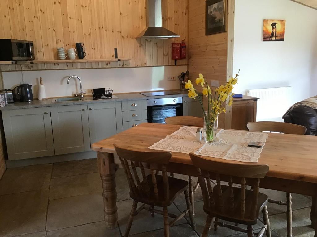 uma cozinha com uma mesa de madeira com um vaso de flores em Beautiful 1-Bed Lodge in Clifford Hereford em Hereford