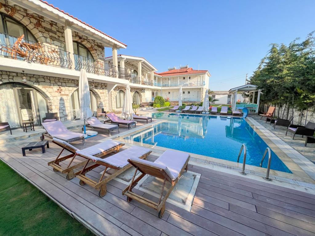 a swimming pool with chaise lounge chairs next to a house at Gonulhan Hotel in Alacati