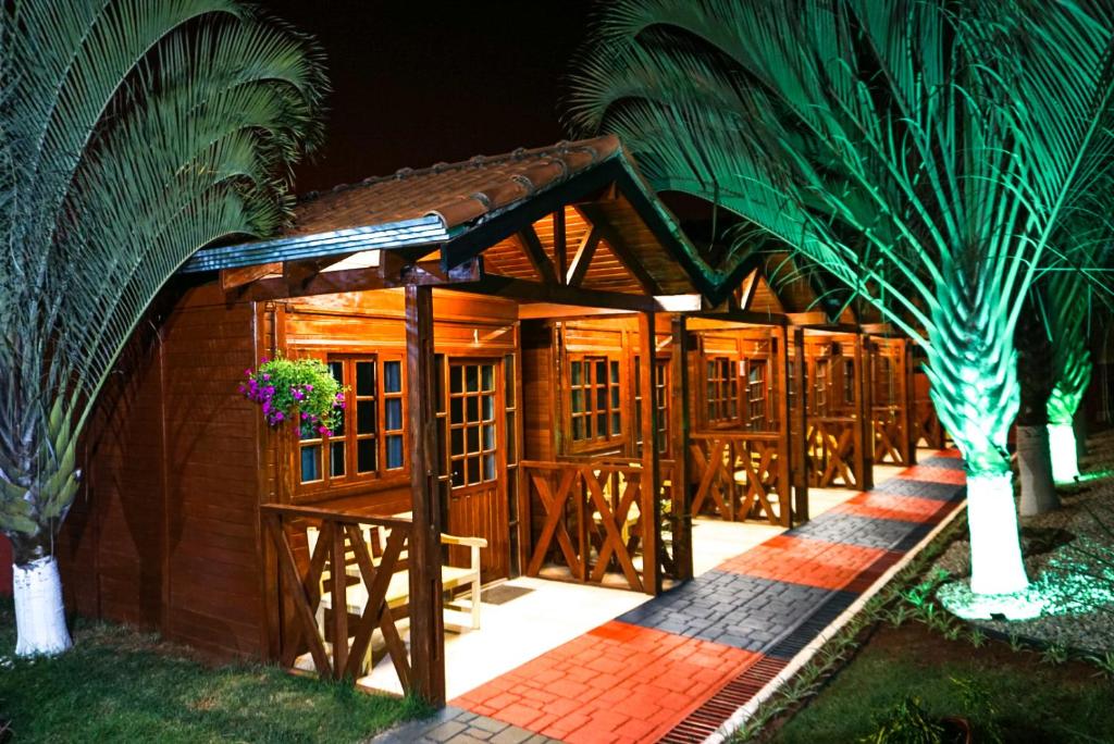 een houten hut met een hek en palmbomen bij Pousada dos Chalés in Olímpia