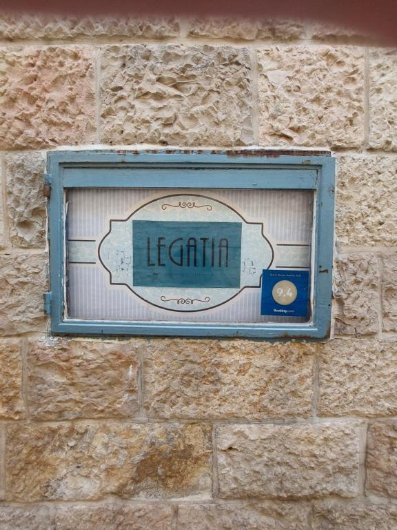 a sign on the side of a brick wall at Legatia in Jerusalem