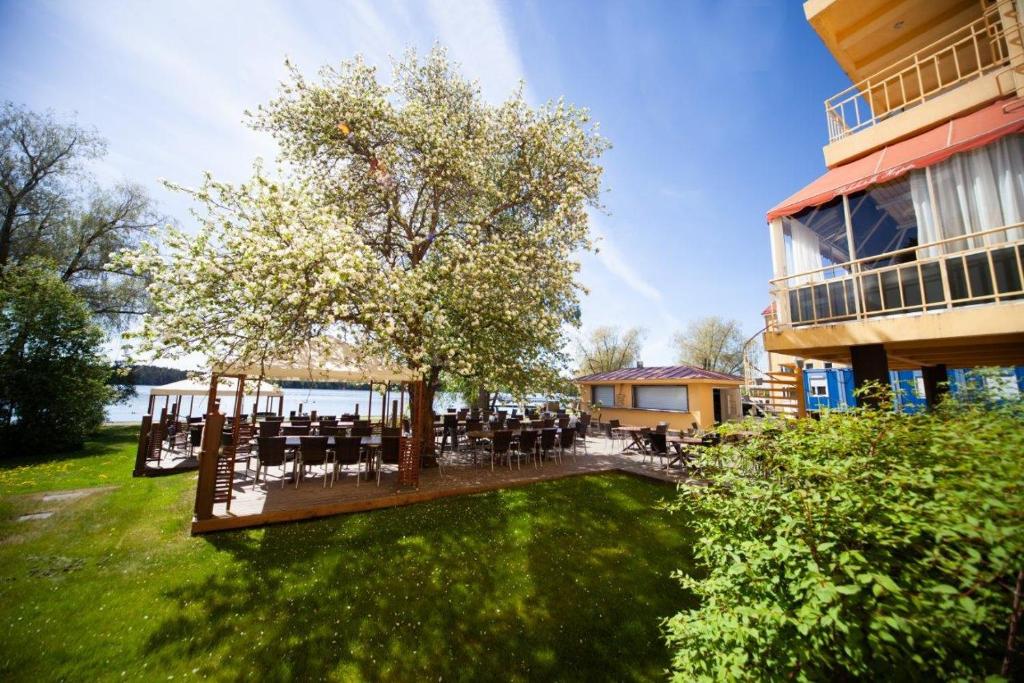 a deck with tables and chairs in a yard next to a building at Hotel Hospitz in Savonlinna