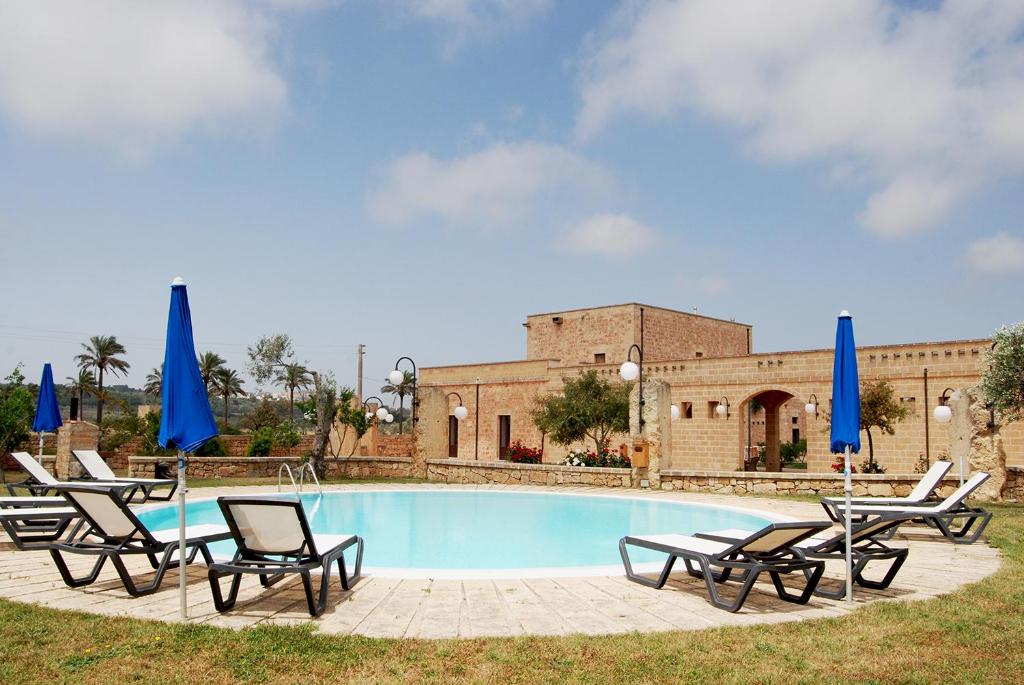einen Pool mit Liegestühlen und blauen Sonnenschirmen in der Unterkunft Masseria Galatea Agriturismo in Alessano