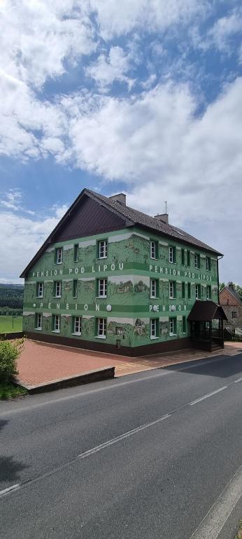 een groot groen gebouw aan de kant van een weg bij Pension Pod Lipou in Nová Ves v Horách