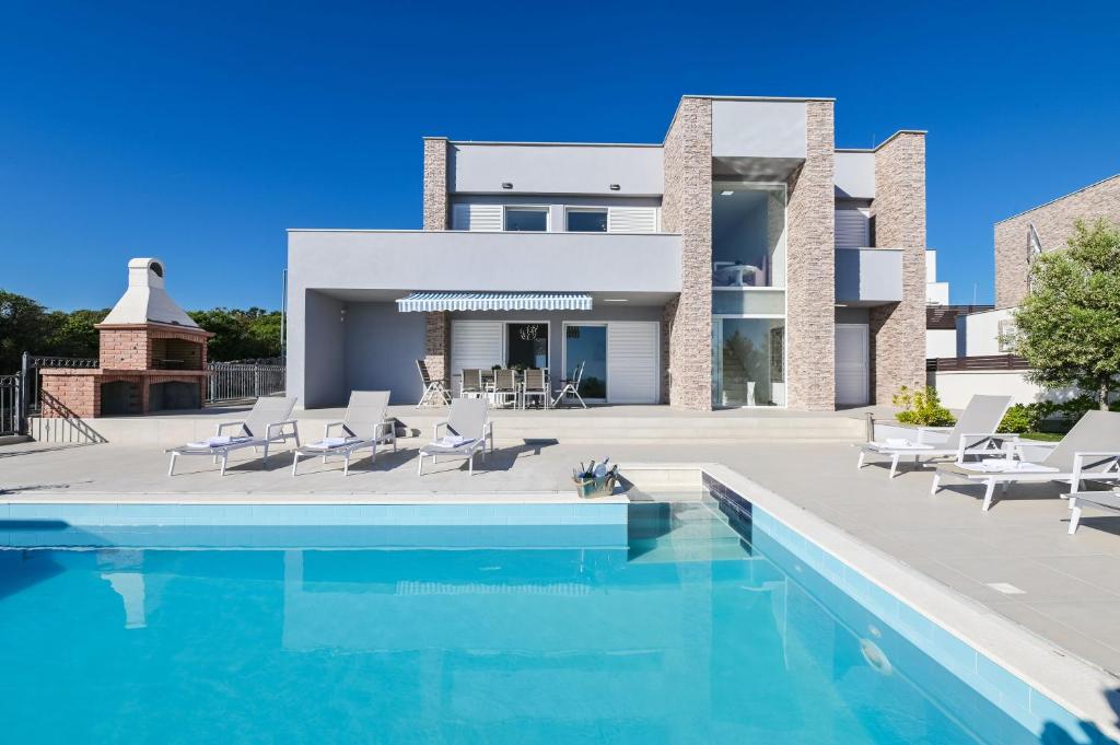 a villa with a swimming pool in front of a house at Villas Royal I with Private Pool in Novalja