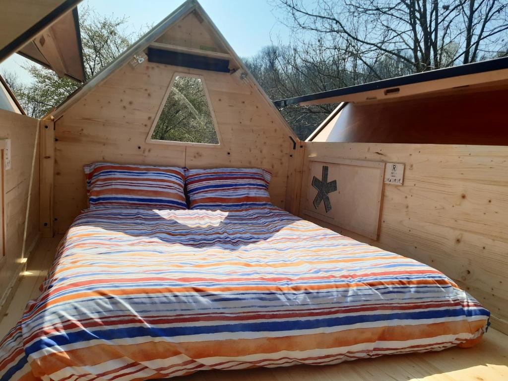 a bed in a wooden cabin with a window at Starsbox Le Moline in Masserano