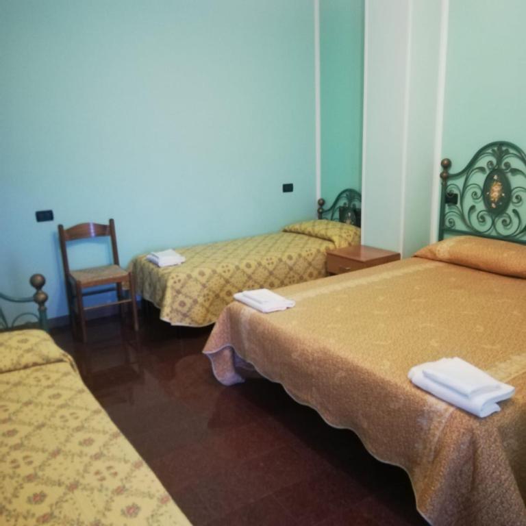pokój hotelowy z 3 łóżkami i krzesłem w obiekcie Hotel Grazia Ristorante w mieście LʼAquila