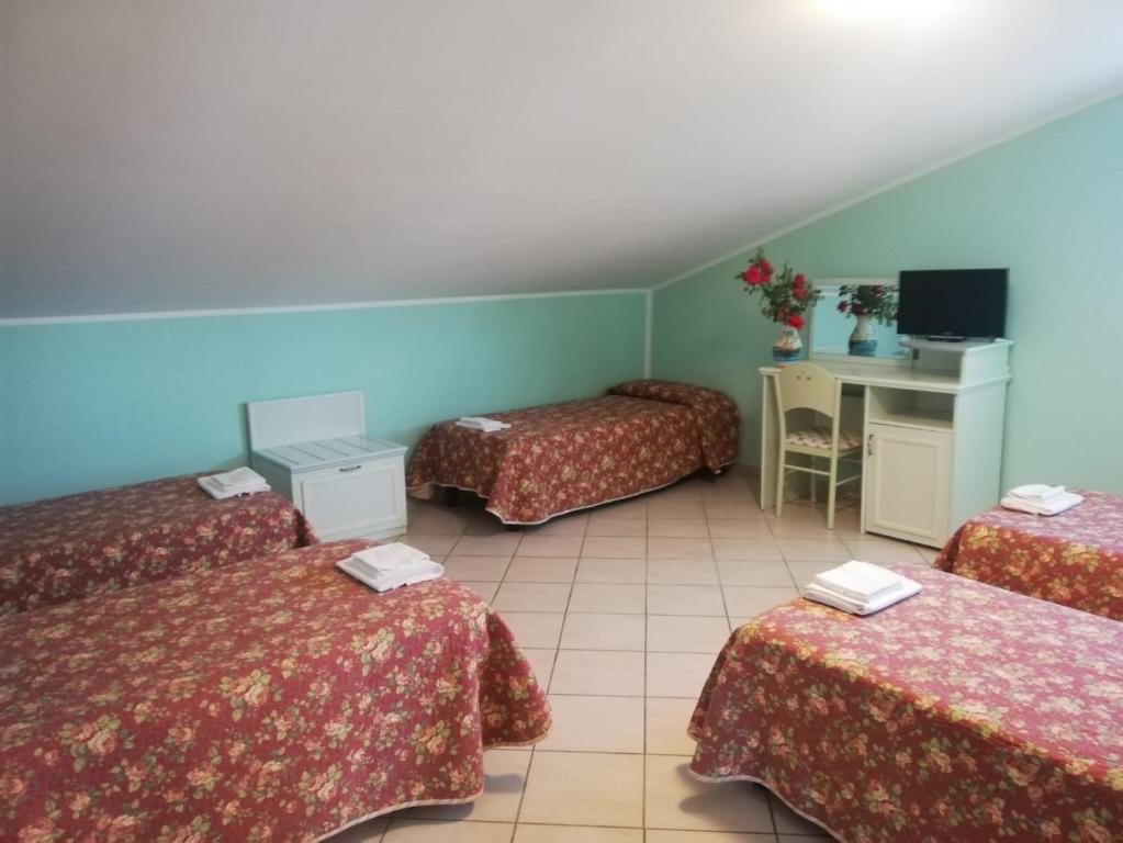 Pokój z 3 łóżkami i biurkiem w obiekcie Hotel Grazia Ristorante w mieście LʼAquila