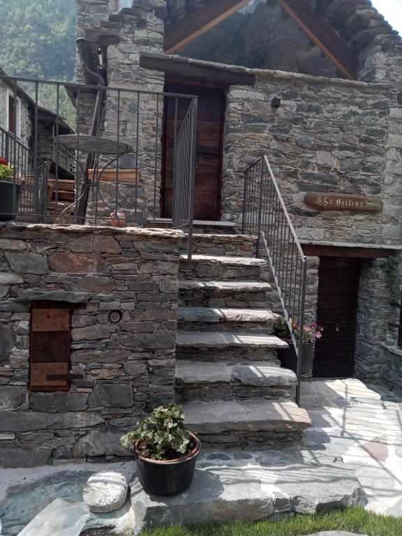 a stone house with a staircase and a chair at Casa Vacanza La Baitina in Antronapiana