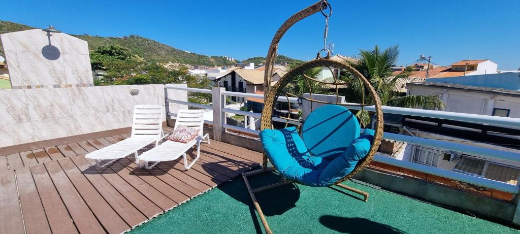 a swing on a deck with two chairs on a deck at PRAIA DOS ANJOS - SUÍTEs in Arraial do Cabo