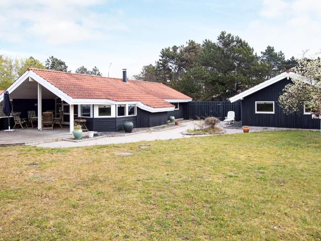 a black house with a red roof and a yard at Holiday home Slagelse XX in Slagelse