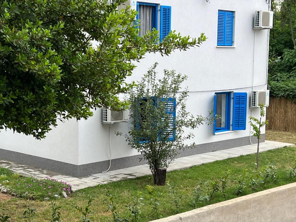 ein weißes Haus mit blauen Fenstern und einem Baum in der Unterkunft Doneto, apartment in private house in Rijeka