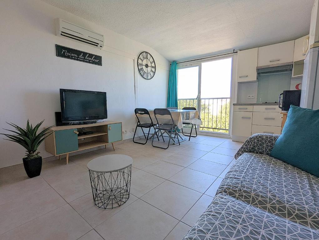 een woonkamer met een bank, een tv en een tafel bij Appartement proche port et mer avec wifi et climatisation in Cap d'Agde