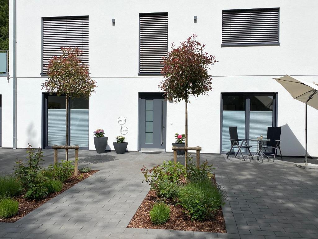 a white building with a patio and a table and chairs at Ferienwohnung Im Dhrontal in Gräfendhron