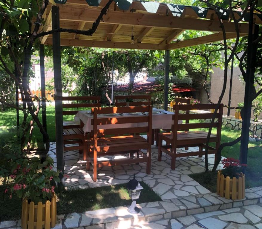 a cat sitting under a pergola with a table and two benches at Vila Culli in Përmet
