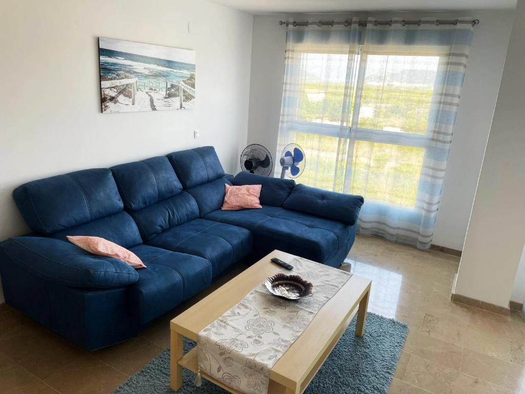 a living room with a blue couch and a coffee table at Apartamento en sol, Ador in Ador