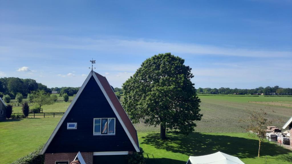 a barn with a blue roof and a tree at Hermans huisje: het mooiste uitzicht van Twente? in Haaksbergen
