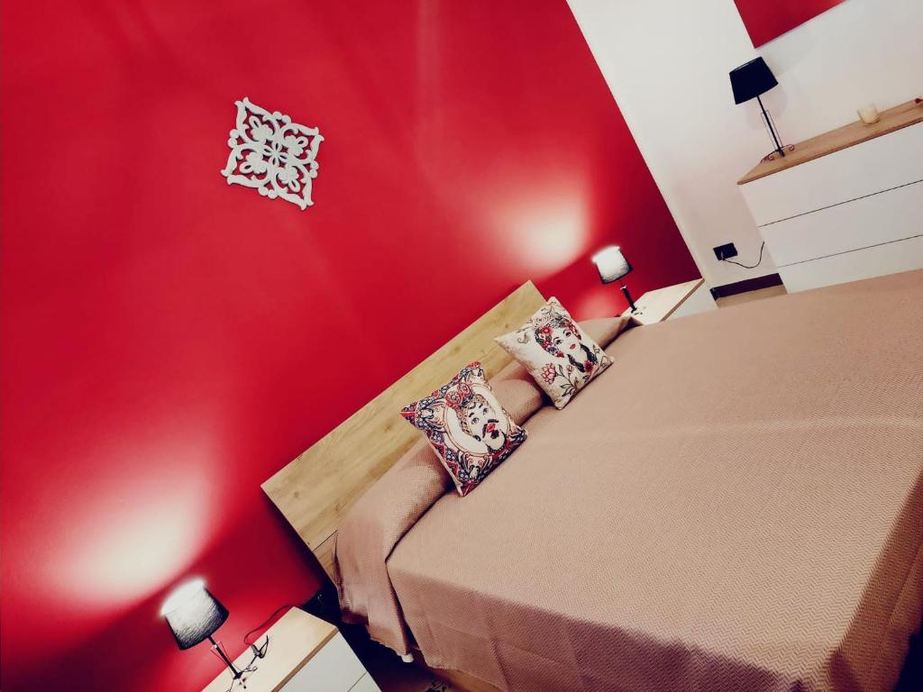 um quarto vermelho com uma cama com almofadas em La Sicilia in casa em Cinisi