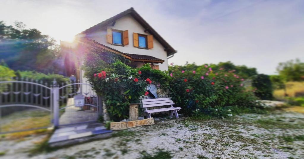 a bench in front of a house with flowers at Erdőterasz Vendégház - Teljes ház in Kehidakustány