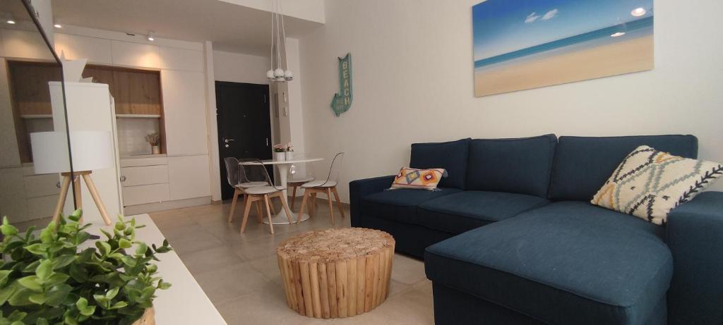 Una sala de estar con un sofá azul y una mesa. en Mosaiko Apartments II, en Tarifa