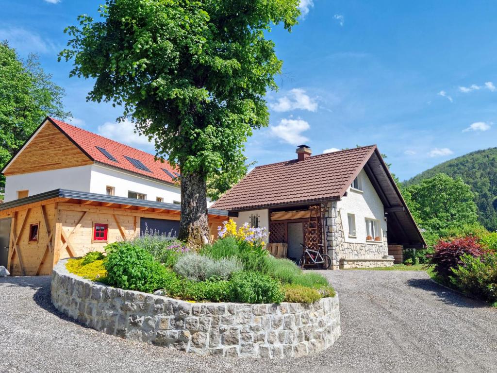 a house with a tree and a stone wall at Lake View Holiday Home in Cerknica