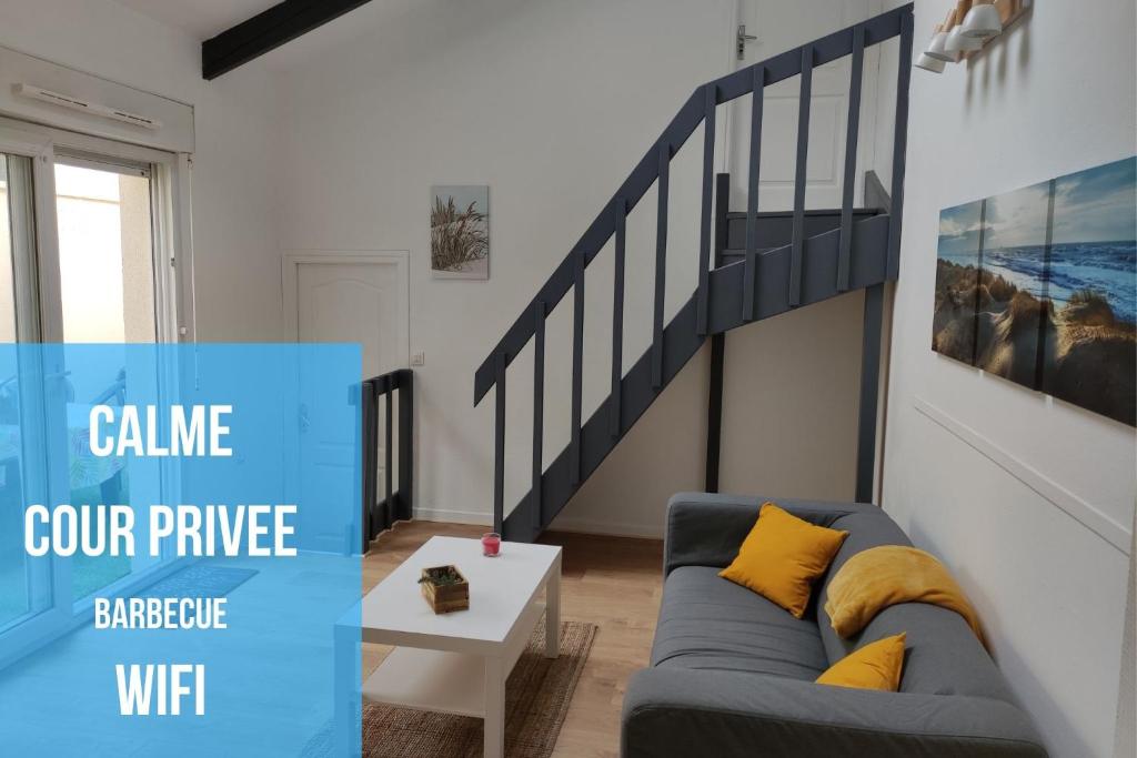a living room with a couch and a staircase at Joli T3 près du phare in Calais