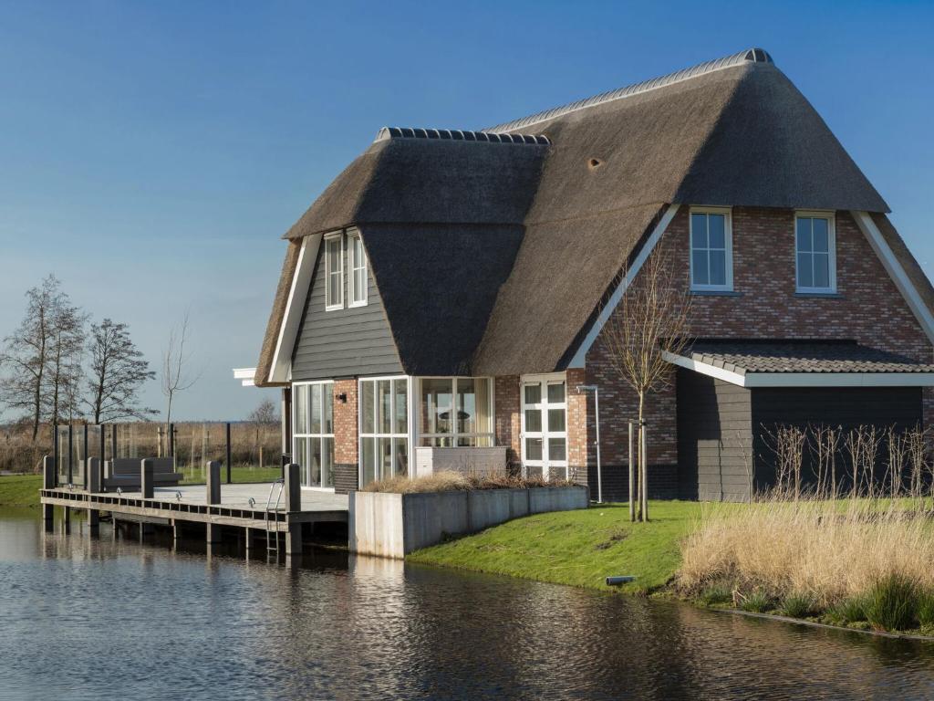 una casa con techo de paja en el agua en Beautiful, thatched villa with a sauna at the Tjeukemeer, en Delfstrahuizen