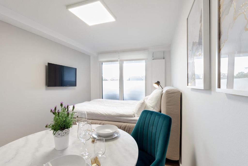 a white room with a table and a bed at Apartment Gartenblick - 1 Zi, Küche, Duschbad, Terrasse sowie Gartenmitbenutzung in Bayreuth