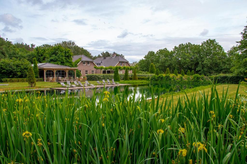 une maison avec un étang en face d'une maison dans l'établissement Landhuis Hotel de Hilkensberg, à Broekhuizen