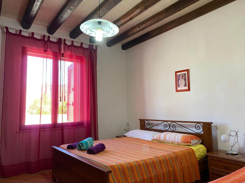 a bedroom with a bed with red curtains and a window at La casa di Andrea in Favignana