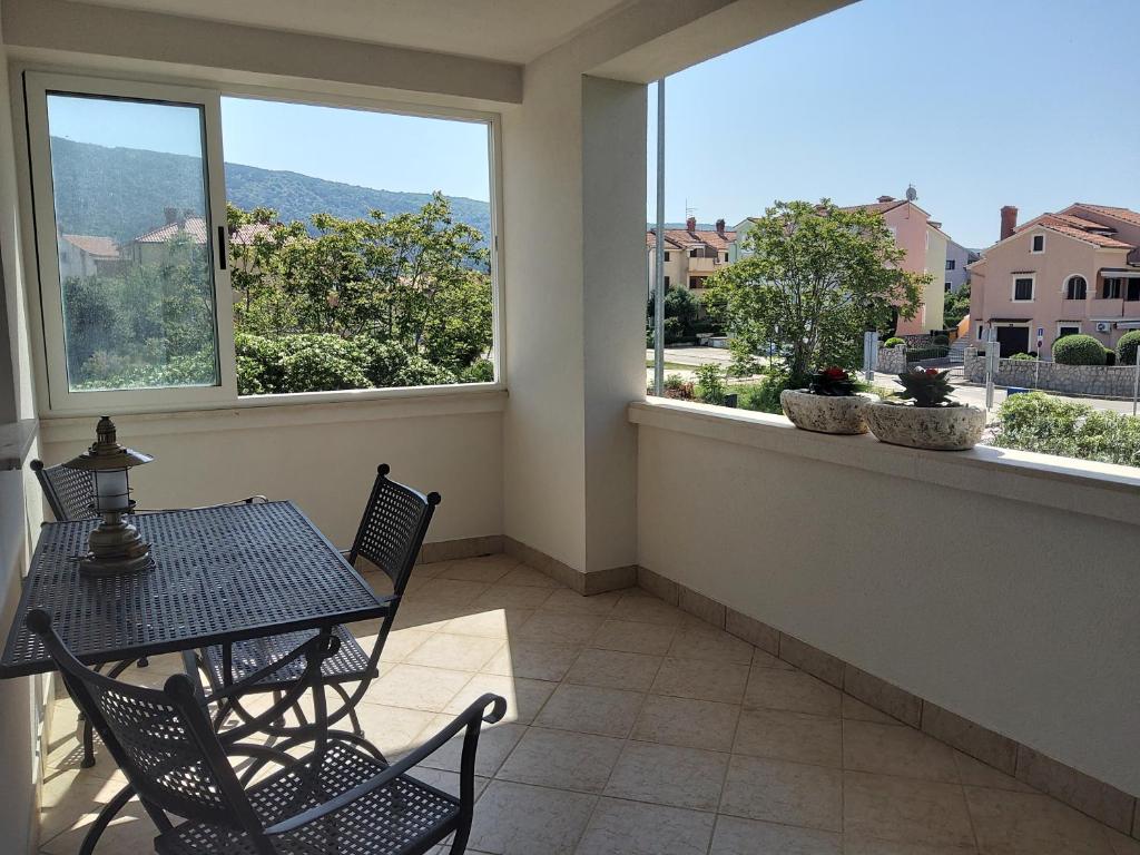 a balcony with a table and chairs and windows at Apartments Rea in Cres
