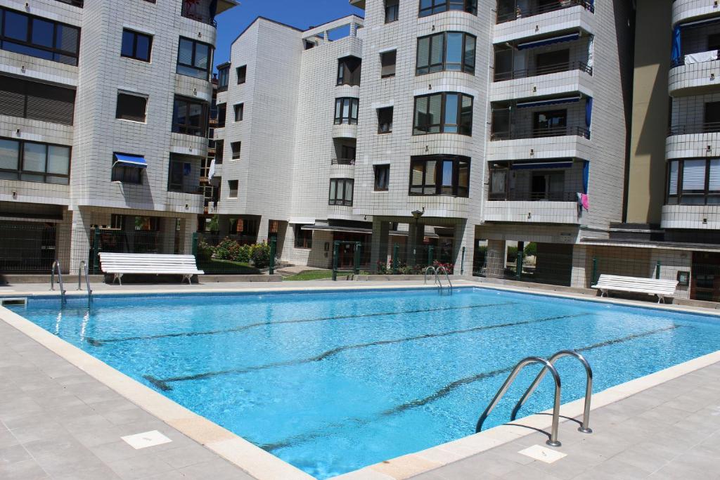 a swimming pool in front of two tall buildings at Apartamentos Zarautz Playa, con piscina y garaje in Zarautz