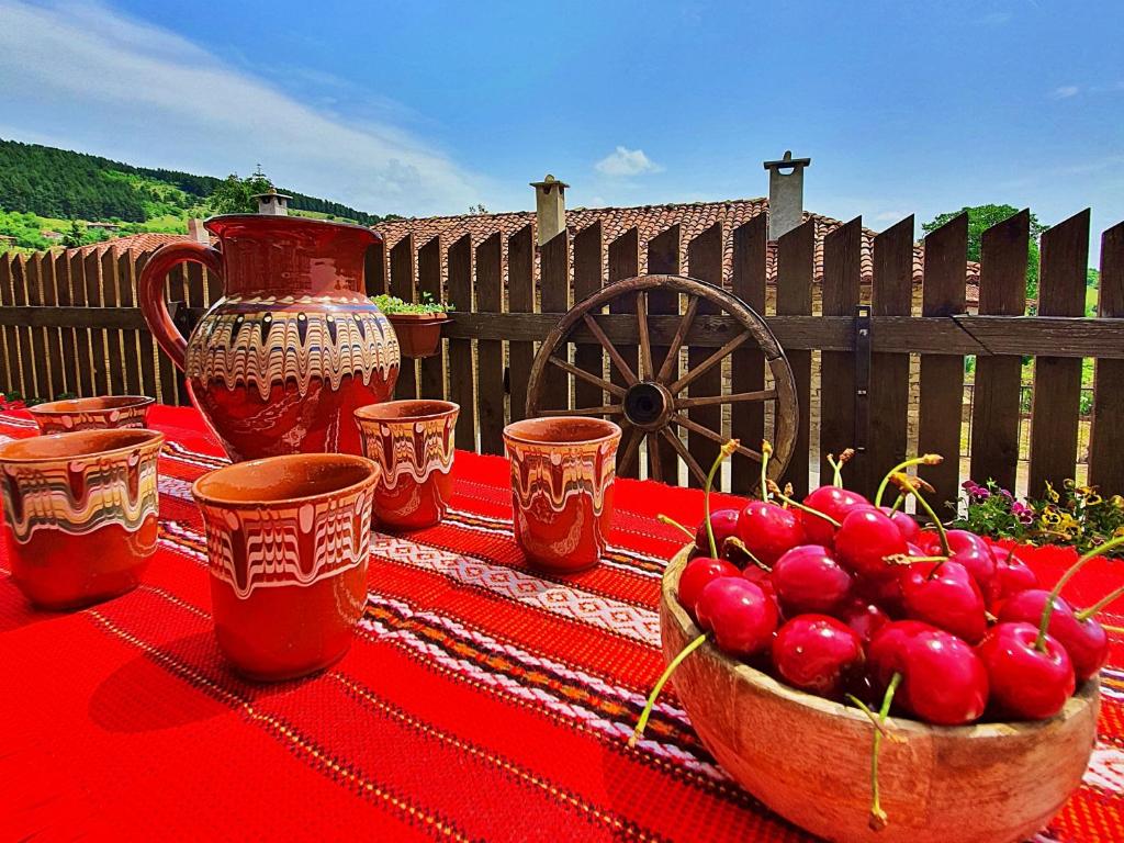 uma mesa com uma tigela de cerejas numa toalha de mesa vermelha em Къща за гости Песента на колелетата - Жеравна em Zheravna