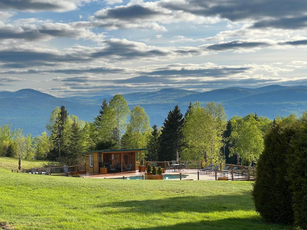 a house in a field with mountains in the background at Paradis de Charlevoix - Loft in Baie-Saint-Paul