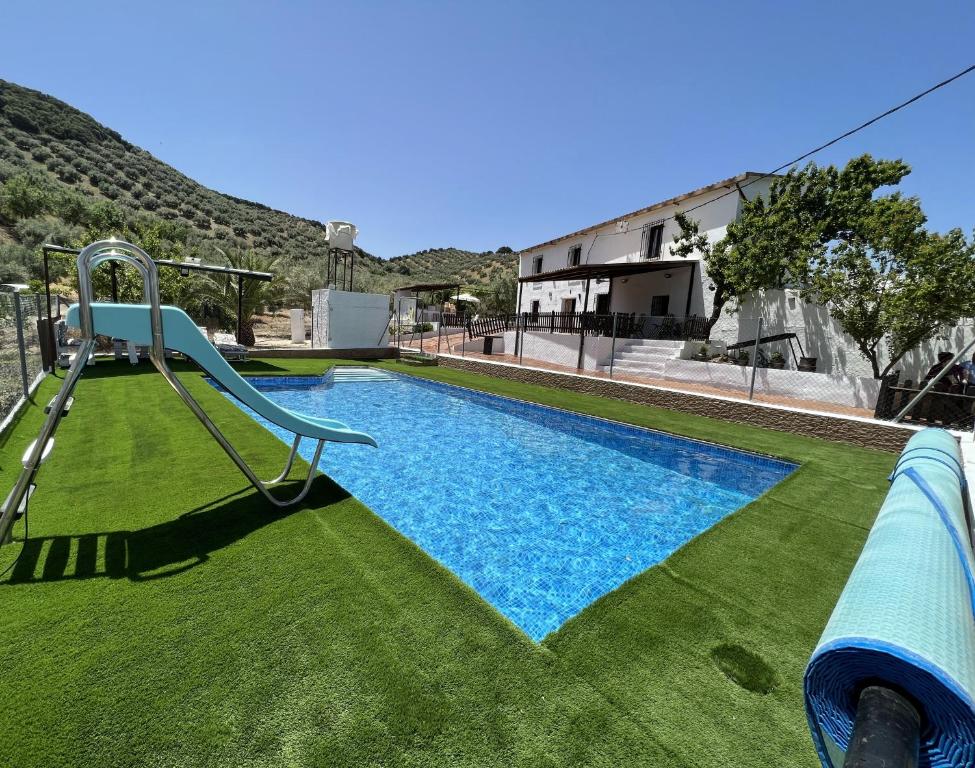 una piscina con tobogán y césped en Alojamiento Rural Cortijo Alameda, Las Lagunillas, en Priego de Córdoba