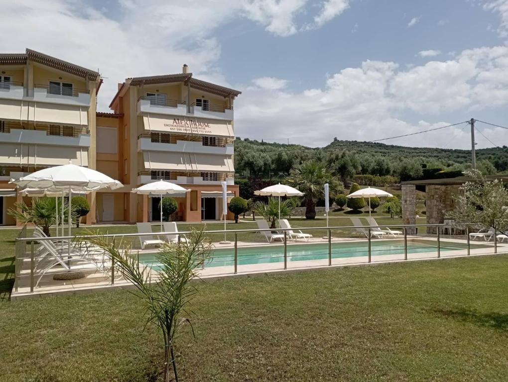 a hotel with a pool and umbrellas next to a building at Alex House in Zakharo