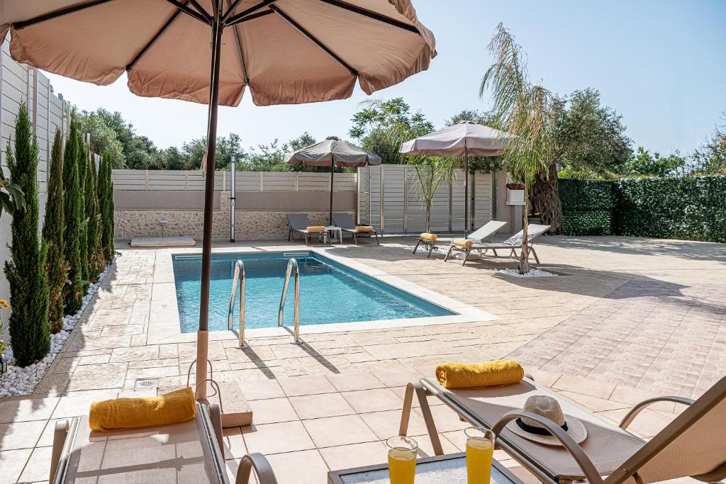 una piscina con sillas y sombrillas y una piscina en Villa Fanouris, en La Canea