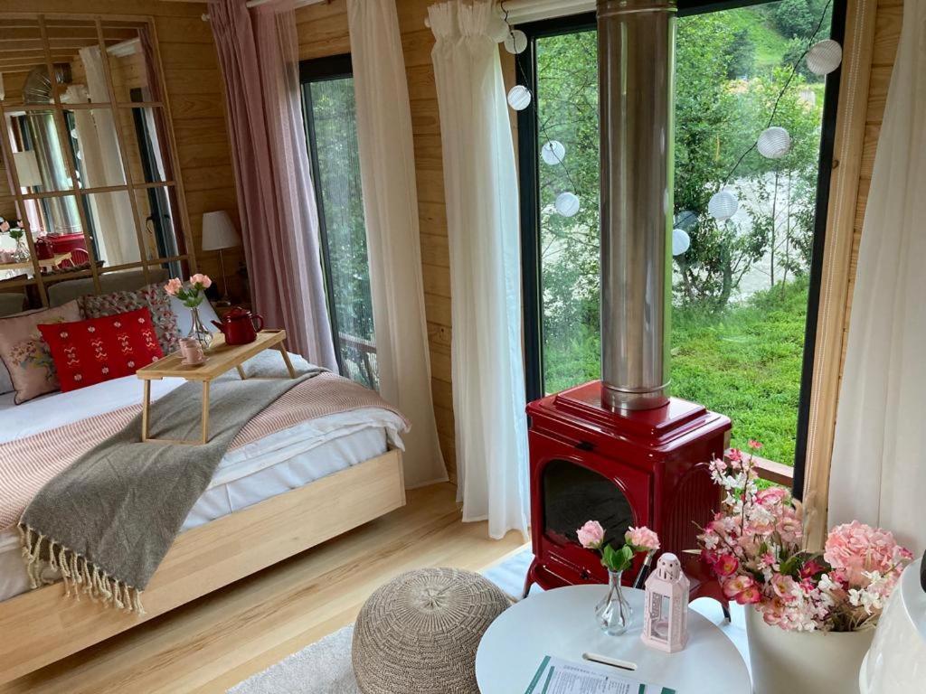 a bedroom with a red wood stove in front of a bed at Vagona Tiny House in Rize