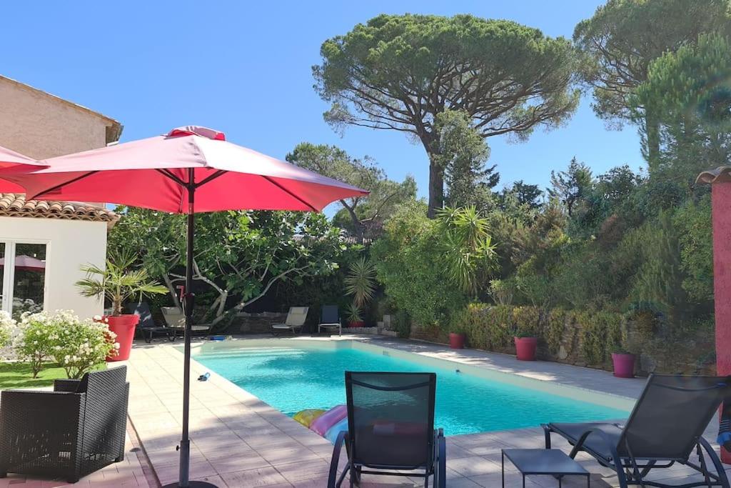 a red umbrella and chairs next to a swimming pool at Ste Maxime Villa 5 etoiles Piscine chauffée et jacuzzi in Sainte-Maxime