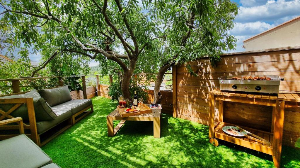a backyard with a grill and a couch and a table at Le Micocoulier in Montesquieu