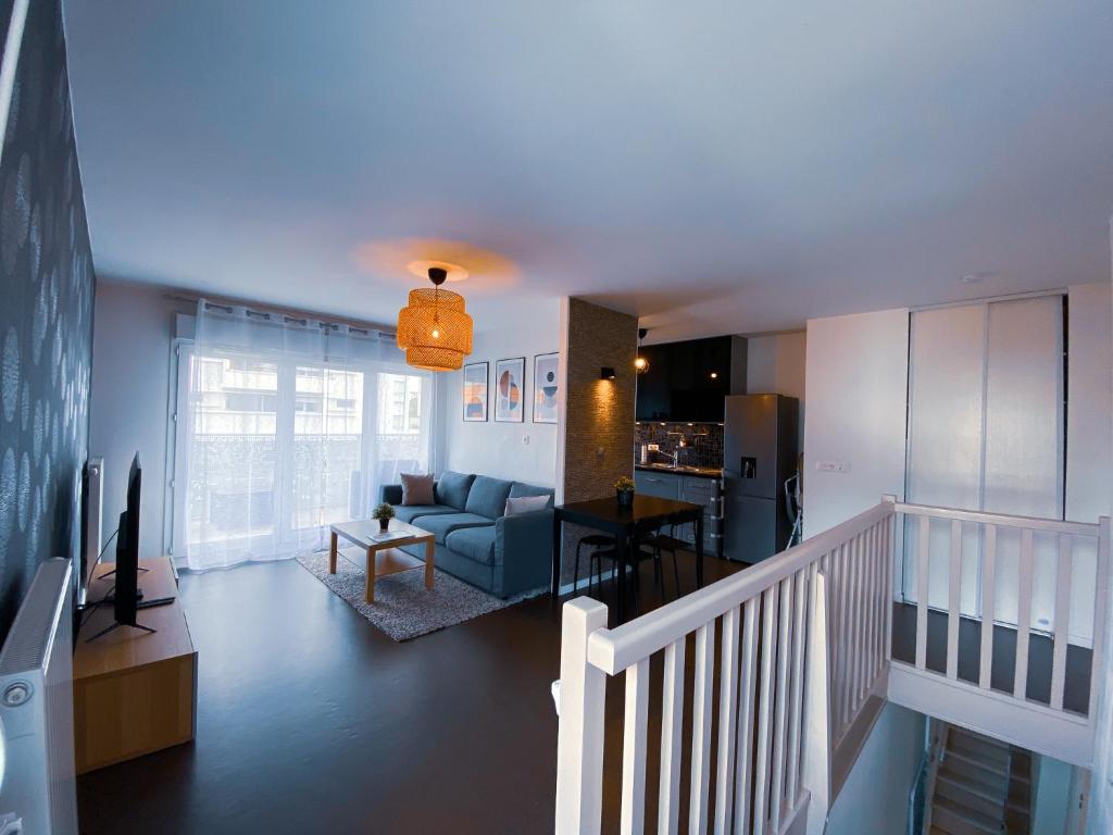 Il comprend un salon avec un canapé bleu et une cuisine. dans l'établissement Le Monseigneur's House - Duplex hyper centre, à Courcouronnes
