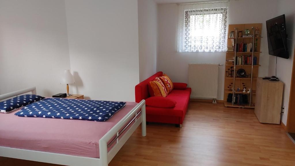 a bedroom with a bed and a red chair at Gemütliche Einliegerwohnung ohne Küche in Hösbach-Rottenberg in Hösbach