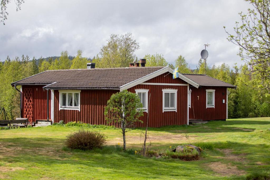 a red house in a yard with a grass at Reyers Bo På Landet in Vansbro