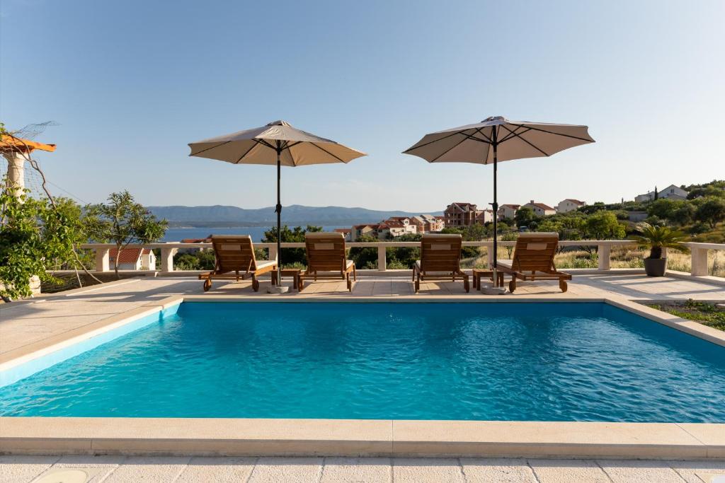 a swimming pool with chairs and umbrellas at Olive Trees Cottage in Bol