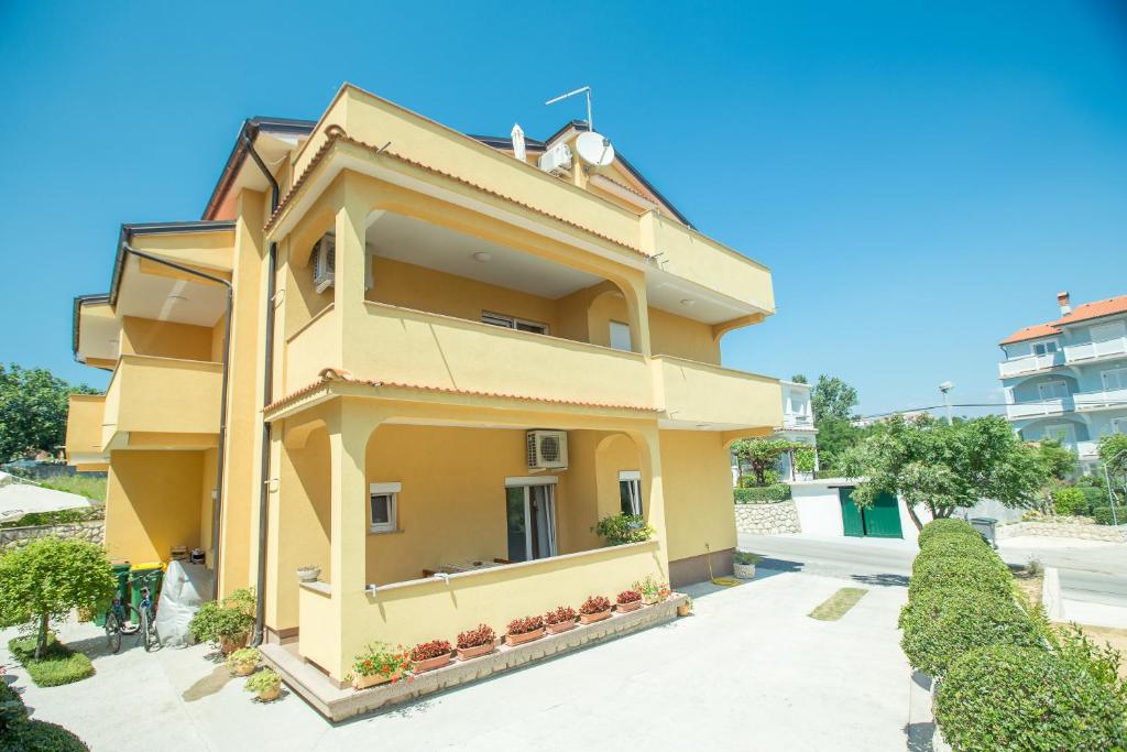 a yellow house with a blue sky in the background at Apartments Meri - 1 in Lopar