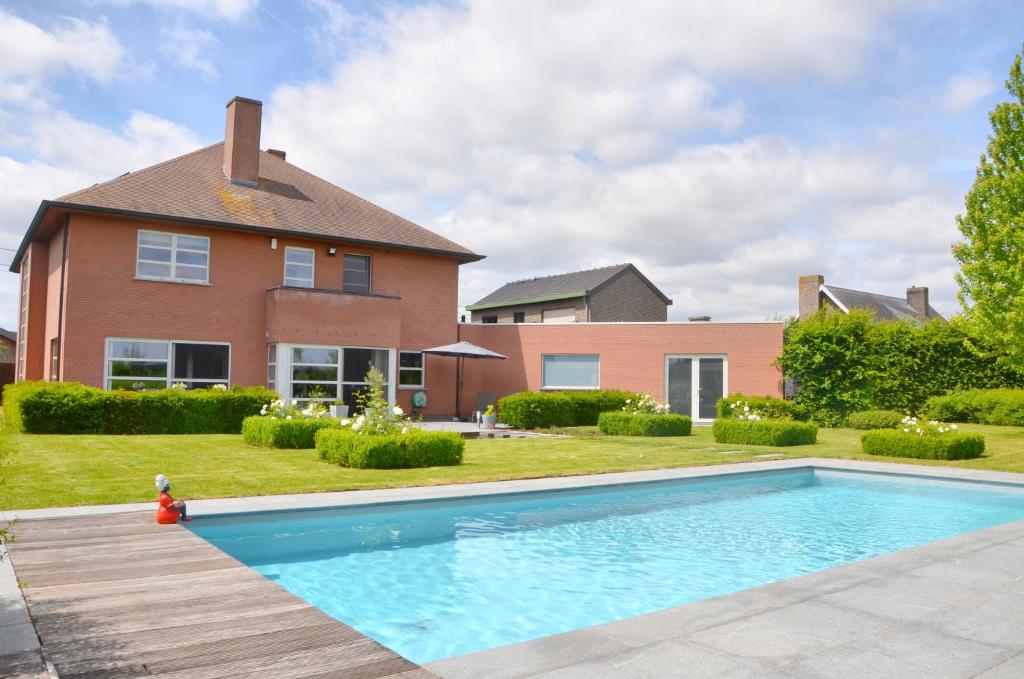 una casa con piscina frente a una casa en Luxe villa in Vlaamse Ardennen met zwembad, en Avelgem